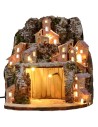 Illuminated snow-covered nativity scene with village and cave